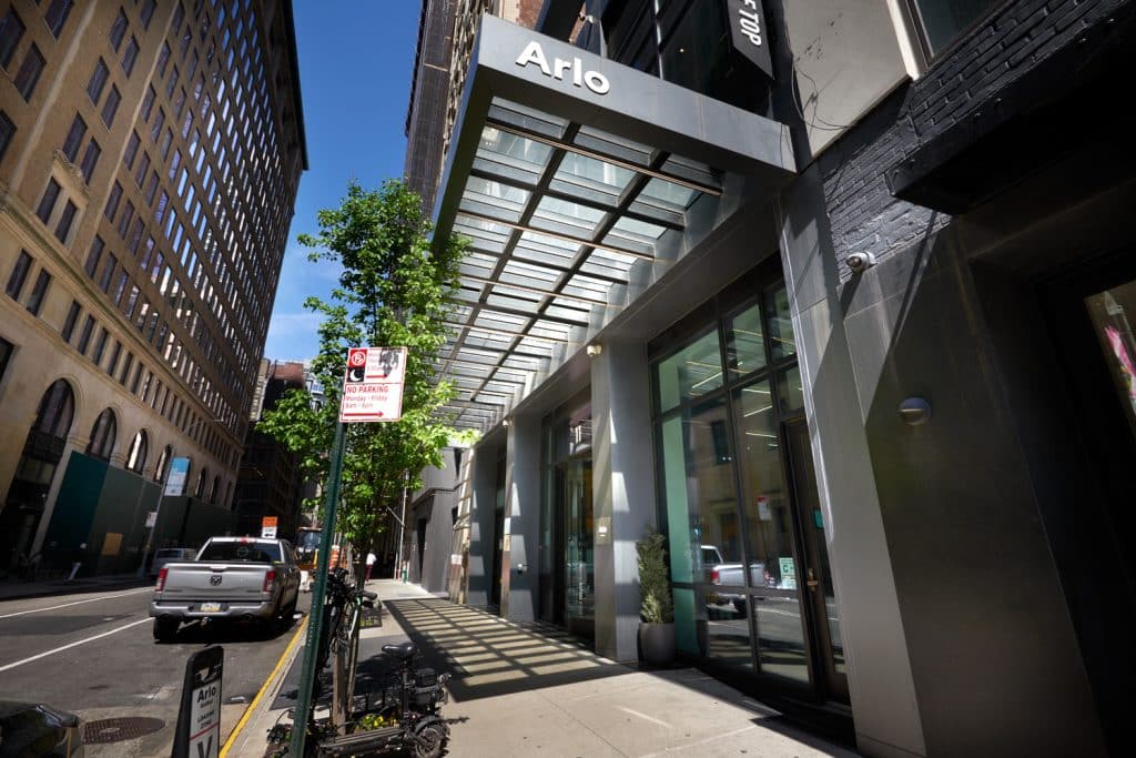 Arlo NoMad hotel entrance with modern architecture, large windows, and greenery, located in Manhattan's NoMad neighborhood.