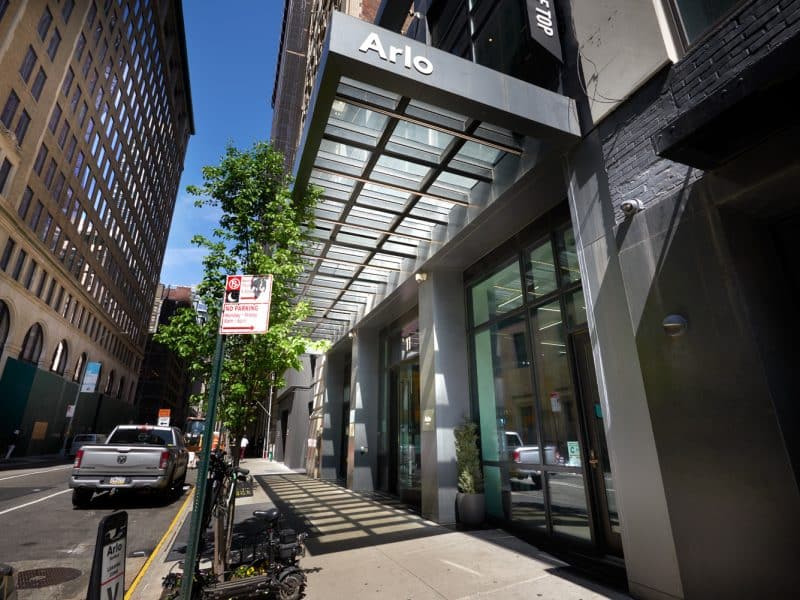 Arlo NoMad hotel entrance in Manhattan's NoMad neighborhood, featuring modern architecture, glass awning, and greenery, highlighting stylish boutique accommodations near major NYC attractions.
