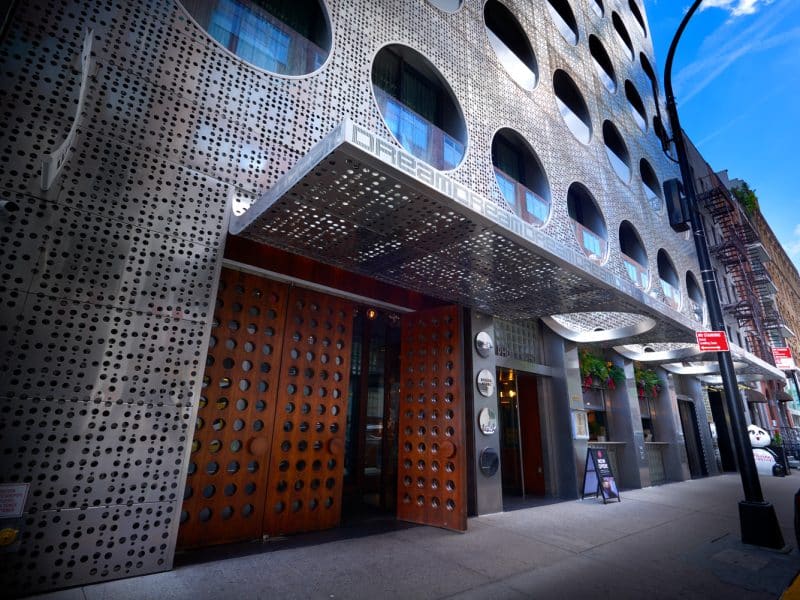 Dream Downtown hotel entrance featuring modern design, perforated metal facade, and wooden doors, located in New York City’s vibrant Meatpacking District.