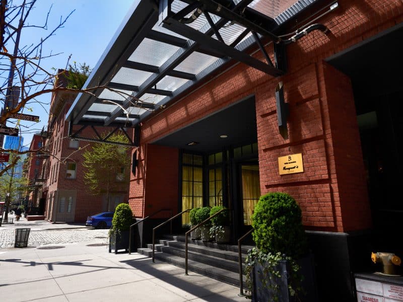 Fouquet’s New York entrance featuring elegant architecture, brick facade, and lush greenery, located in Tribeca, Manhattan, offering a luxurious boutique hotel experience.