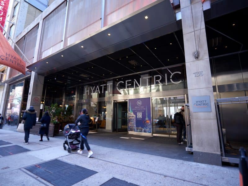 Hyatt Centric Times Square hotel entrance with modern architecture, welcoming guests, and vibrant city atmosphere.