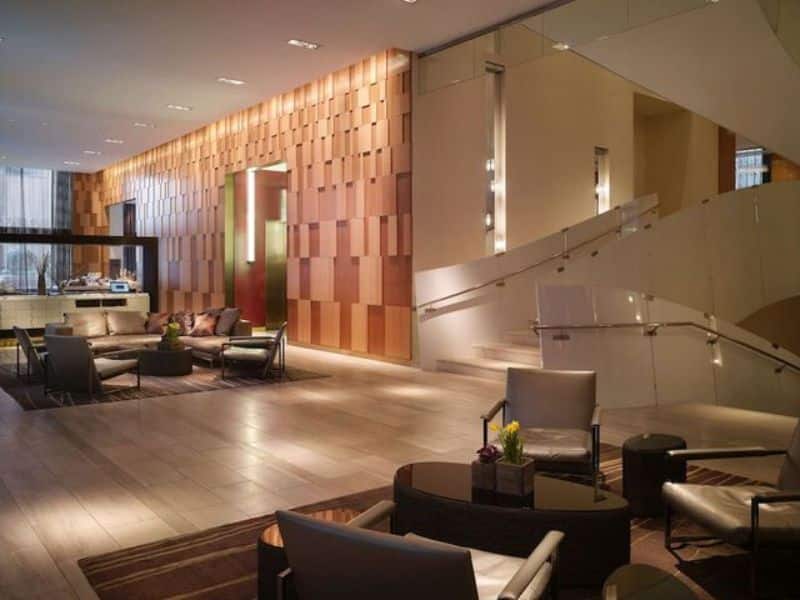 Modern lobby of Hyatt Centric Wall Street featuring stylish seating, wooden accent wall, and elegant decor, emphasizing a refined atmosphere in New York City's Financial District.