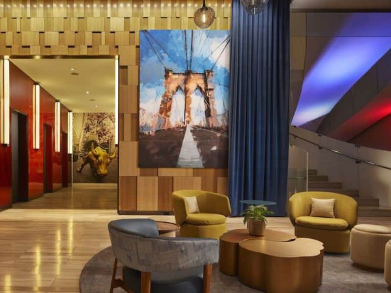 Lobby area of Hyatt Centric Wall Street featuring modern seating, a large artwork of the Brooklyn Bridge, and stylish decor elements.
