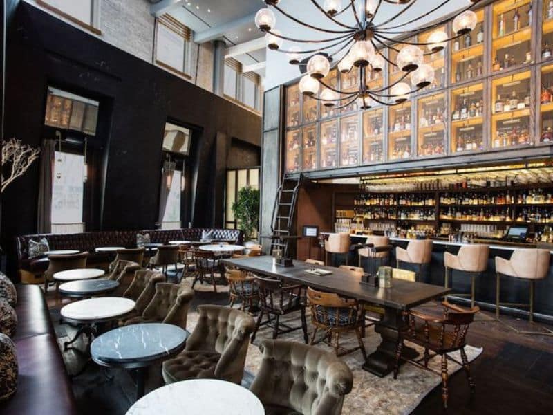 Stylish bar and lounge area at Hyatt Union Square New York featuring plush seating, marble tables, and a well-stocked backlit bar.