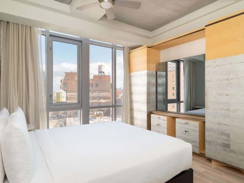 Stylish guest room at Hyatt Union Square New York with modern decor, large windows offering city views, and a comfortable bed.