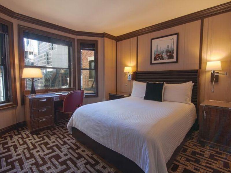 Cozy hotel room at DoubleTree by Hilton New York LaGuardia Airport, featuring a queen bed, desk, and large windows with city views.