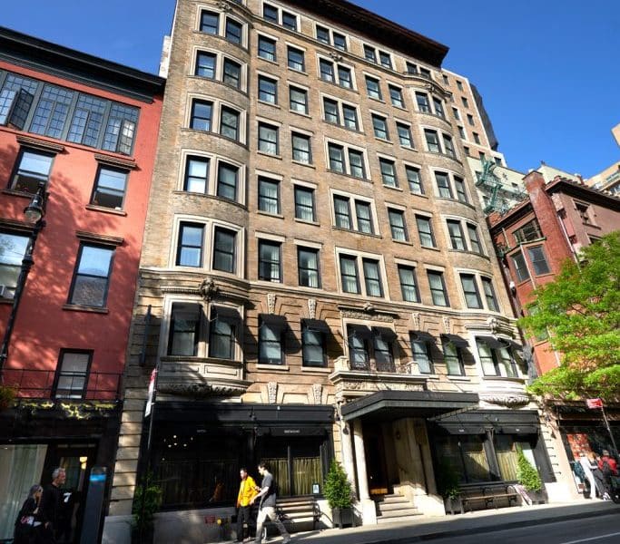 Historic Beaux-Arts exterior of The Marlton Hotel in Greenwich Village, Manhattan, highlighting architectural charm and modern sophistication, with pedestrians in front.