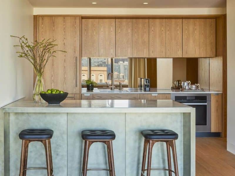 Luxury kitchen area in Pendry Manhattan West hotel featuring modern design, marble countertop, wooden cabinetry, and stylish bar stools.