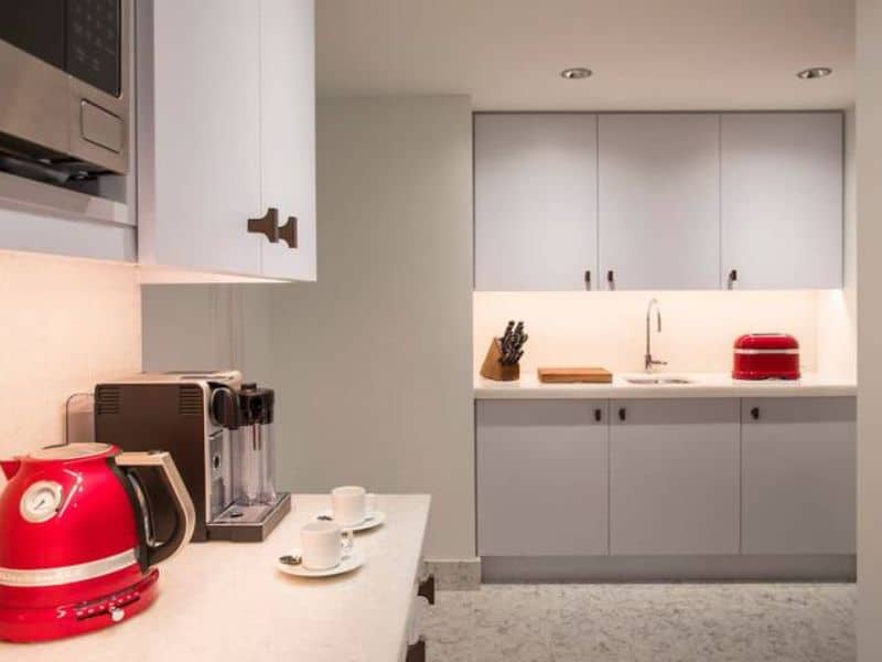 Kitchenette in Ritz-Carlton Central Park room featuring a red kettle, coffee maker, and modern cabinetry, emphasizing luxury and convenience for guests.