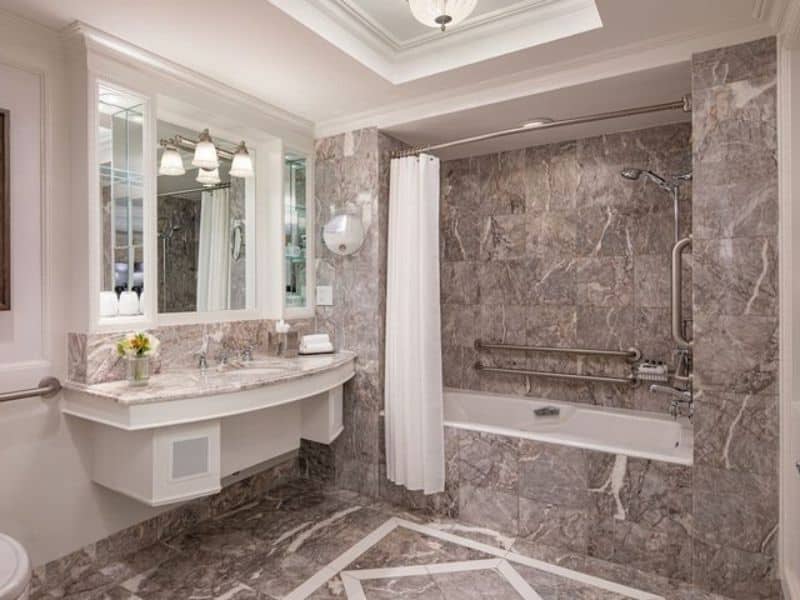 Luxurious hotel bathroom featuring marble finishes, a bathtub with shower, elegant lighting, and a spacious vanity, highlighting Ritz-Carlton Central Park's upscale accommodations.