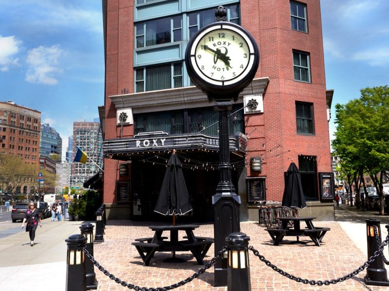 Roxy Hotel entrance with vintage clock, outdoor seating, and Tribeca's vibrant atmosphere.