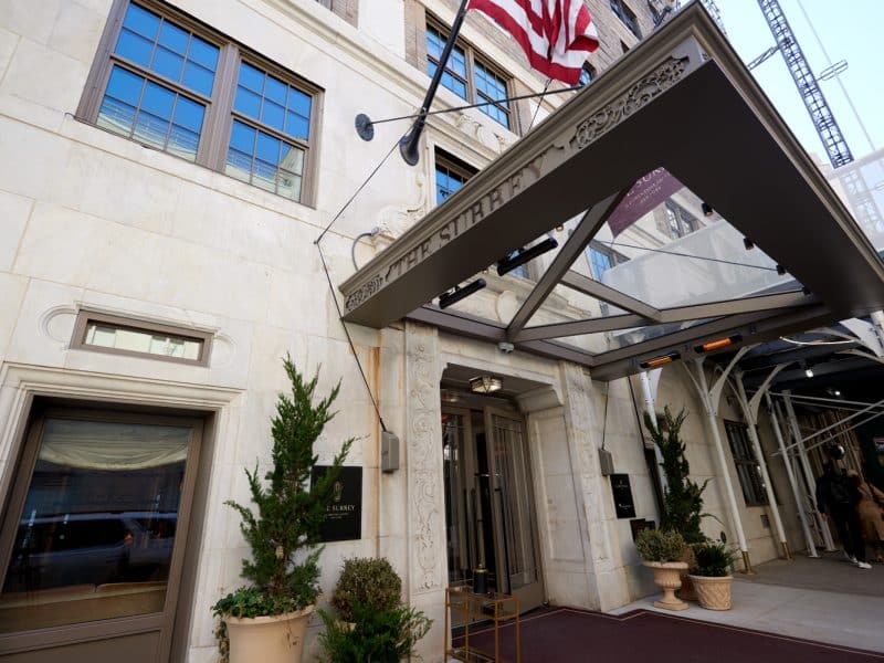 The Surrey, A Corinthia Hotel entrance featuring elegant architecture, awning, and potted greenery in Manhattan's Upper East Side.