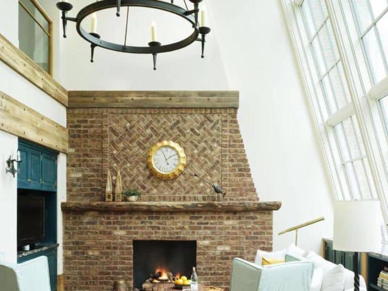 Cozy living space in The Greenwich Hotel featuring a rustic brick fireplace, elegant chandelier, and stylish decor, highlighting the hotel's luxury and inviting atmosphere.