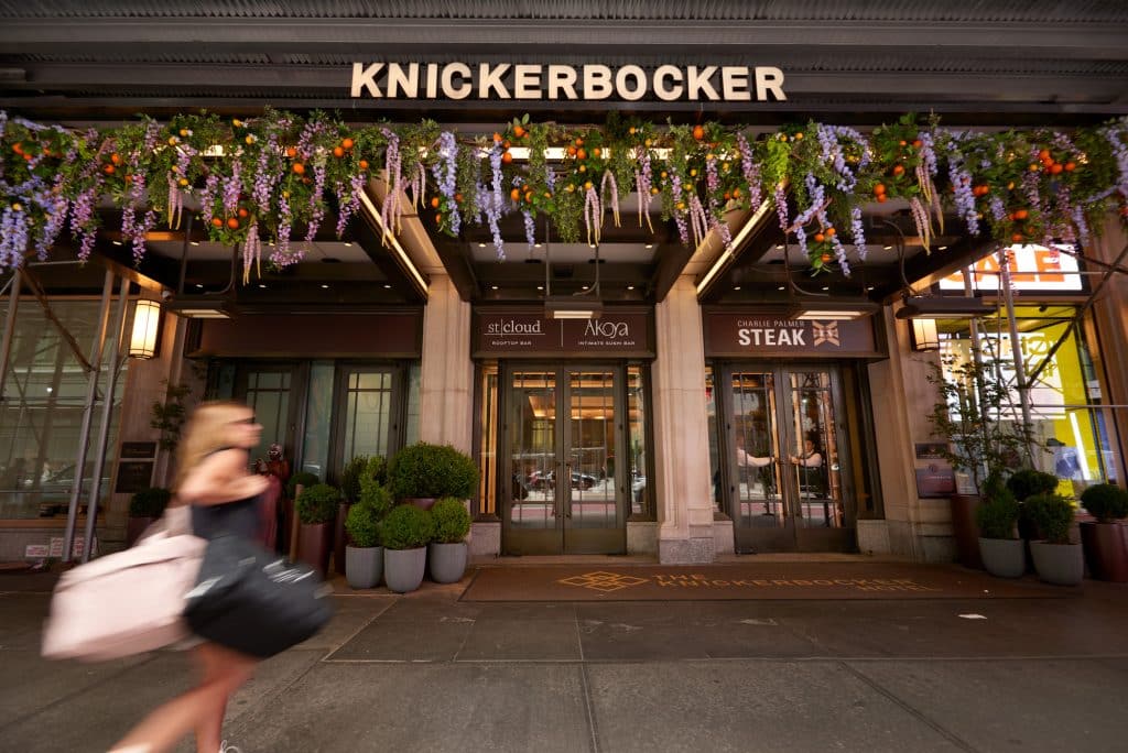 Knickerbocker Hotel entrance with floral decor, featuring stcloud rooftop bar and Charlie Palmer Steak, in the heart of Times Square.