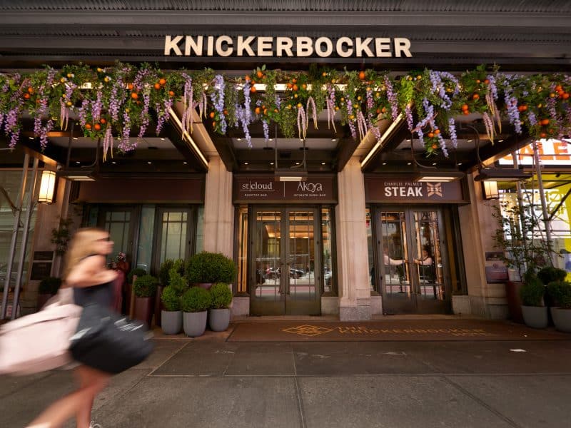 Knickerbocker Hotel entrance with floral decorations, featuring stcloud rooftop bar and Charlie Palmer Steak, located in Times Square, showcasing luxury and elegance.