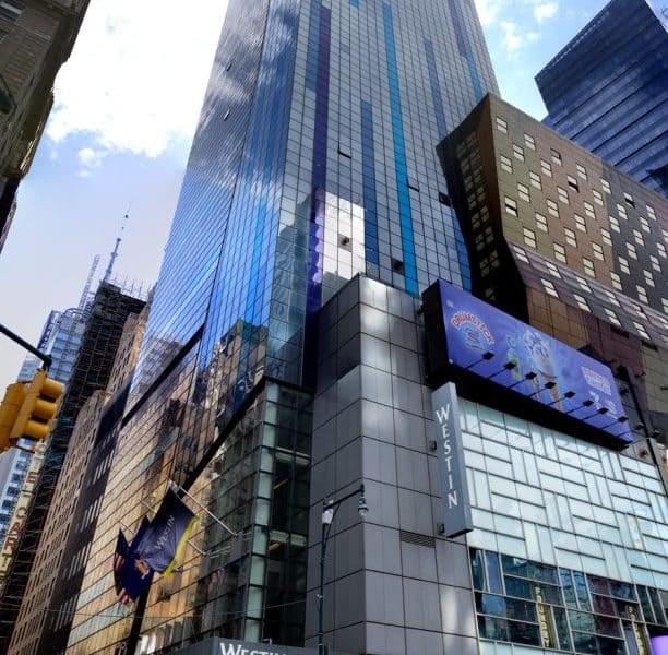 Westin New York at Times Square hotel exterior, featuring modern glass architecture, prominent signage, and surrounding urban landscape.