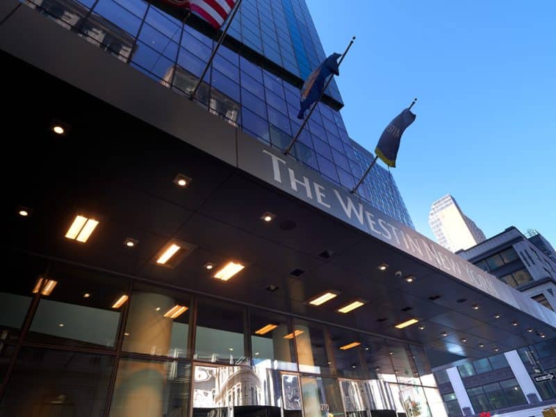 The Westin New York at Times Square building exterior with flags, modern architecture, and illuminated signage.