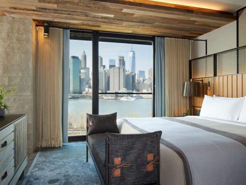 Luxurious hotel room at 1 Hotel Brooklyn Bridge featuring eco-conscious design, with stunning views of the Manhattan skyline and Brooklyn waterfront.