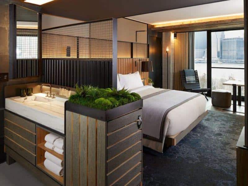Luxurious eco-friendly hotel room at 1 Hotel Brooklyn Bridge featuring a modern design, king-size bed, and views of the Manhattan skyline, with a focus on natural elements like greenery and sustainable materials.