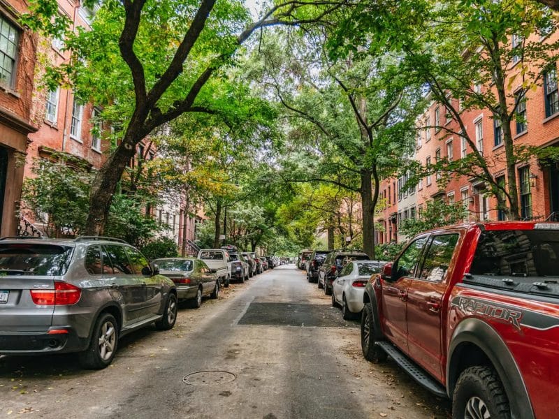 Tree-lined street in downtown NYC with parked cars, reflecting the charming atmosphere of Taylor Swift's hotspots tour.