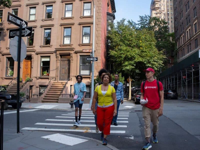 Group of people walking in Brooklyn Heights, showcasing vibrant neighborhood architecture and greenery, part of a culinary tour experience.