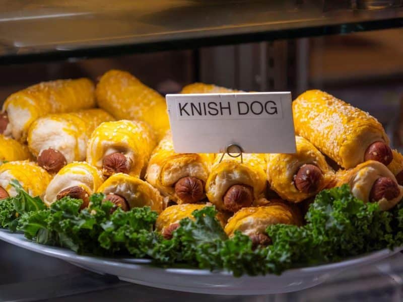Knish dogs displayed on a platter with lettuce, showcasing a popular multicultural snack in Brooklyn's food scene.