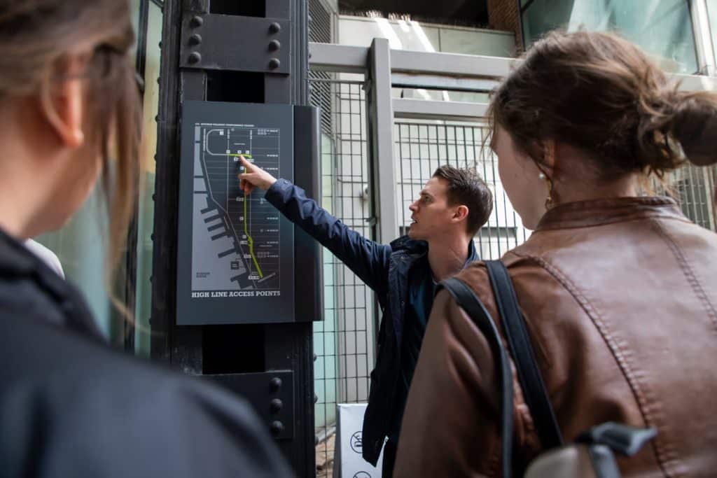 Tour guide explaining High Line access points to a group, with a map displayed showing the route and nearby landmarks.