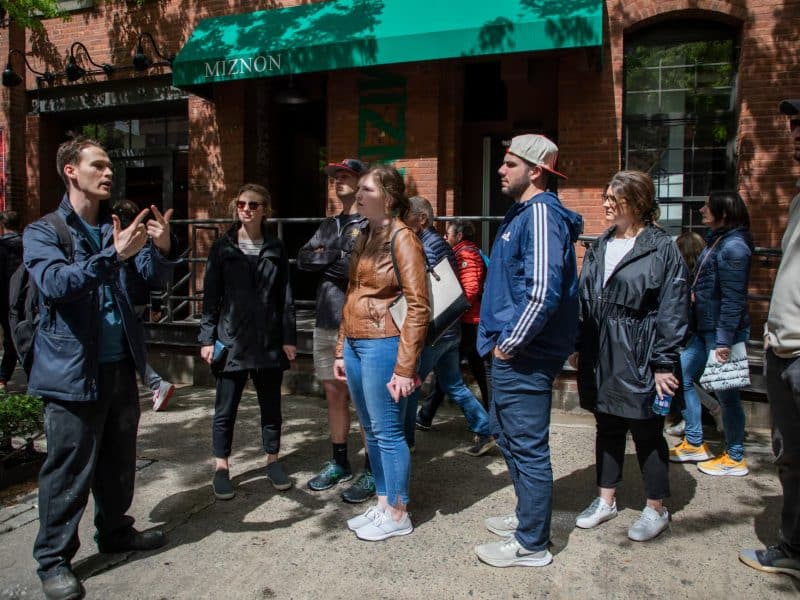 Group of tour participants listening to a guide in front of a restaurant during a Chelsea Market and High Line food tour, showcasing the vibrant atmosphere of the Meatpacking District.