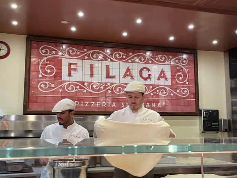 Chefs preparing pizza dough at Filaga Pizzeria, showcasing culinary skills and vibrant restaurant atmosphere in Chelsea Market.