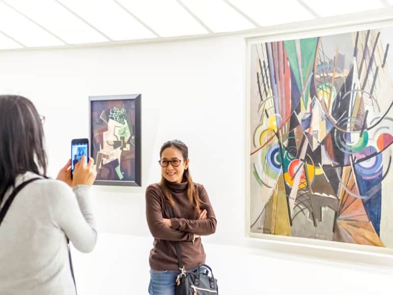 Visitor enjoying contemporary art at the Guggenheim Museum, with a colorful abstract painting on display and another artwork in the background.