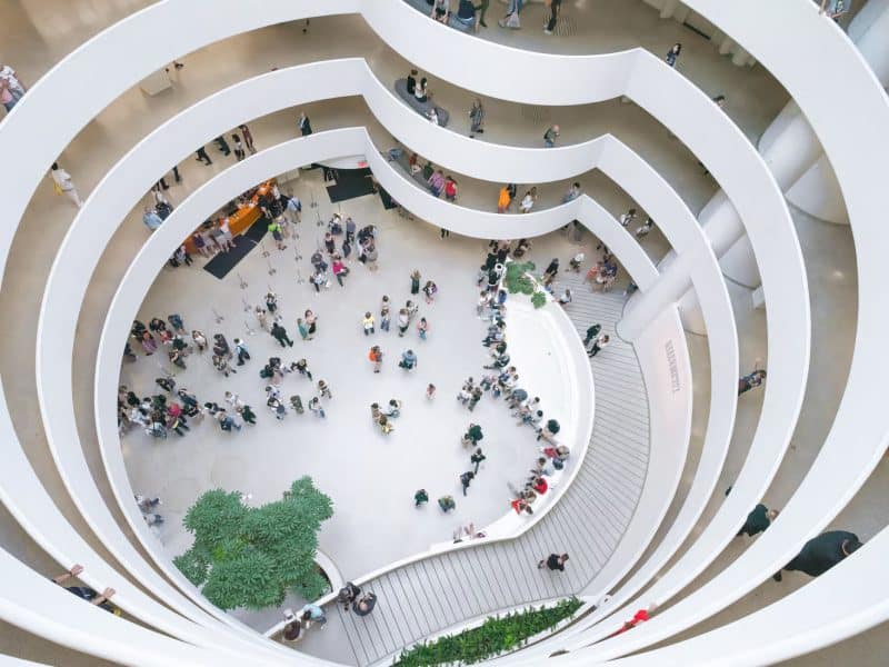 Interior view of the Solomon R. Guggenheim Museum, showcasing the iconic spiral architecture by Frank Lloyd Wright, with visitors exploring the space and engaging with exhibitions.