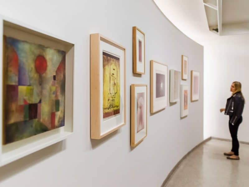 Woman observing framed modern art pieces on a curved gallery wall in the Solomon R. Guggenheim Museum, showcasing contemporary art exhibitions.