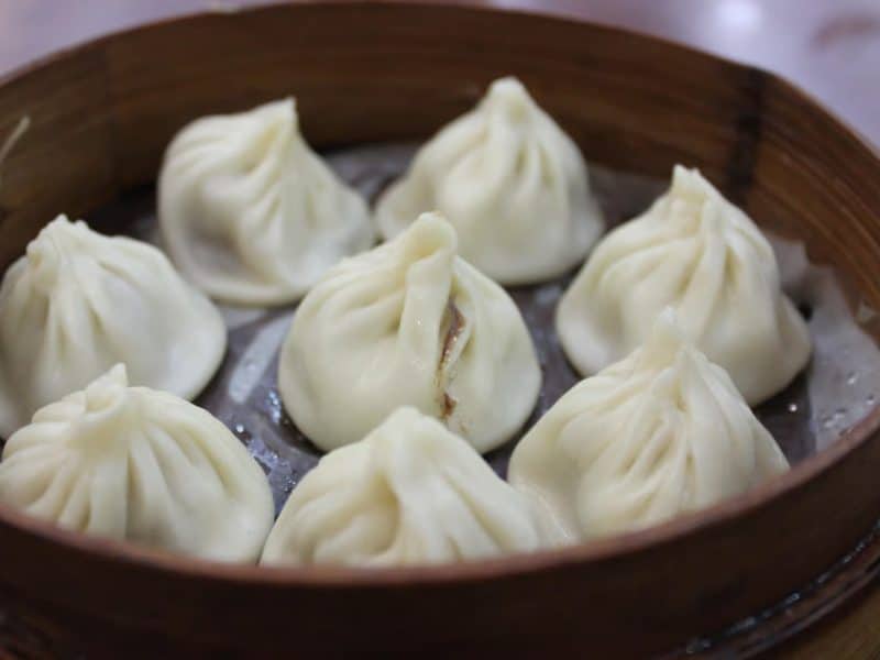Steaming basket filled with freshly made soup dumplings, showcasing the authentic flavors of Flushing's vibrant culinary scene.