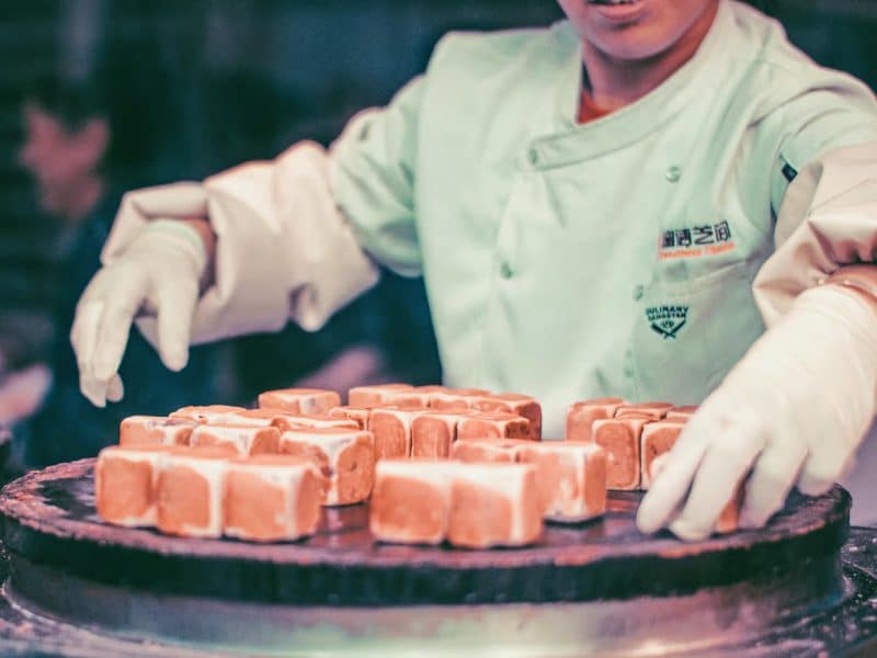 Chef preparing traditional Chinese desserts on a steaming hot plate at Flushing's vibrant Chinatown, showcasing the culinary delights of NYC&rsquo;s Largest Chinatown Foodie Adventure.