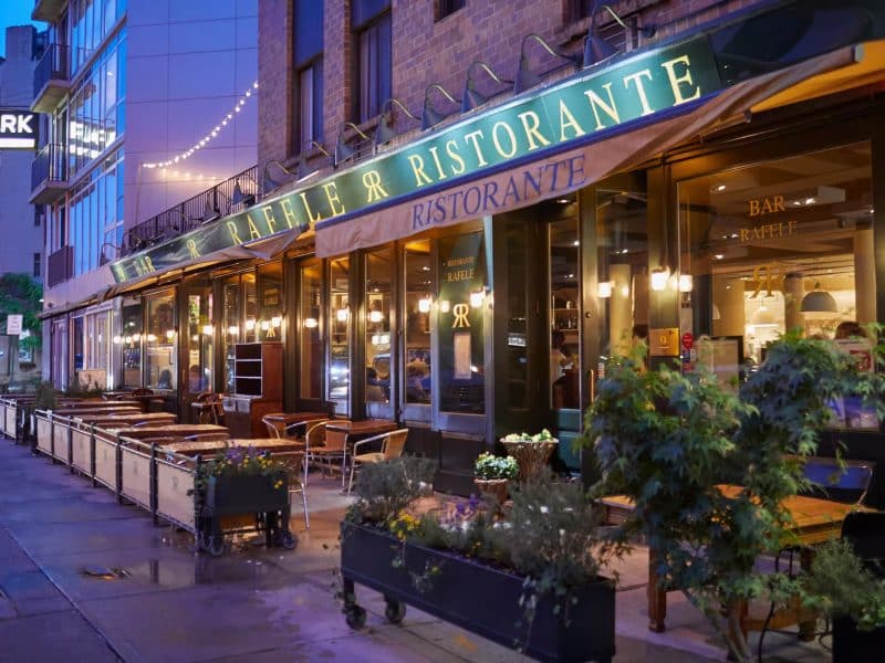 Restaurant Raffaele in Greenwich Village, featuring outdoor seating and illuminated signage, showcasing NYC's culinary charm.