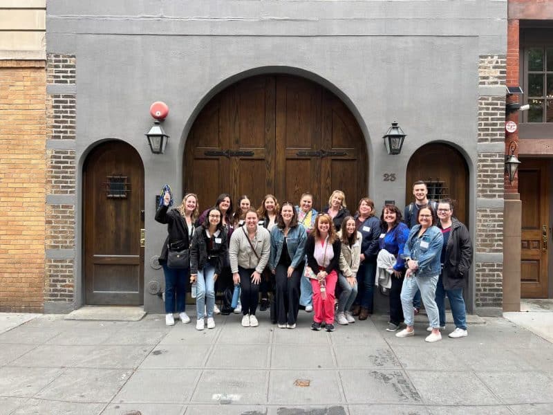 Group of people posing in front of a historic building in Greenwich Village, showcasing the vibrant community spirit of NYC's food culture walking tour.