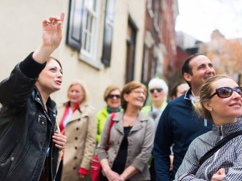 Group of diverse tourists engaging with a guide during the Original Greenwich Village Food & Culture Walking Tour, showcasing the vibrant atmosphere of NYC's West Village.