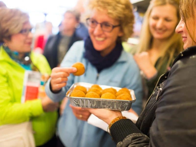 Group of food tour participants enjoying tastings, sharing a tray of golden fried snacks during the Original Greenwich Village Food & Culture Walking Tour.