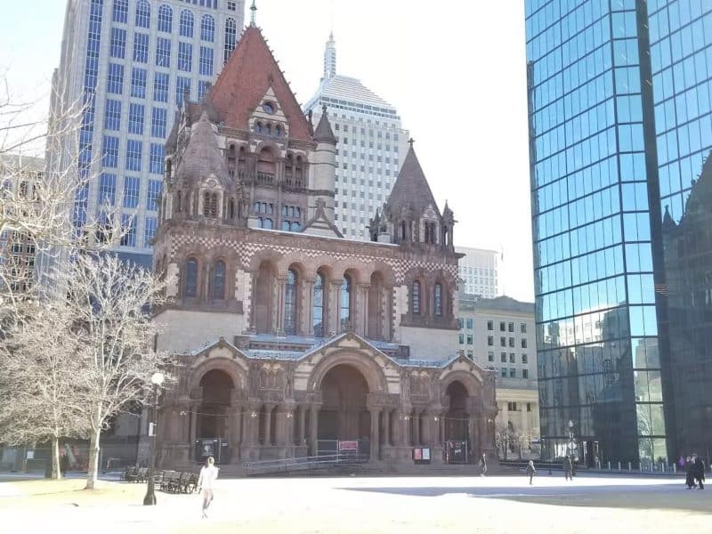 Historic Boston architecture featuring the Boston Public Library, surrounded by modern skyscrapers, in a vibrant urban setting.