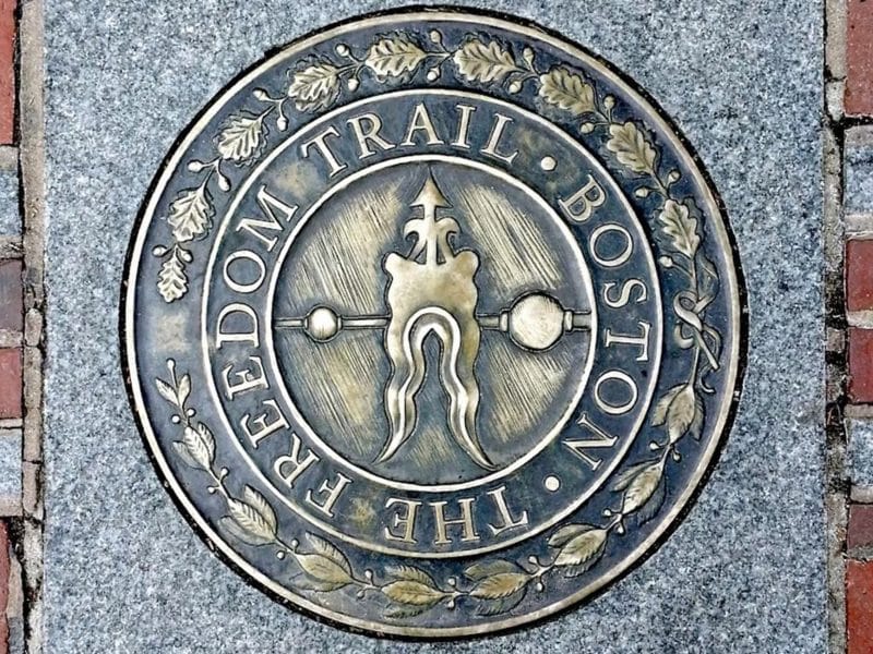 Freedom Trail medallion in Boston, featuring the inscription "THE FREEDOM TRAIL" and decorative elements, symbolizing historical significance and guiding tourists through Boston's rich heritage.