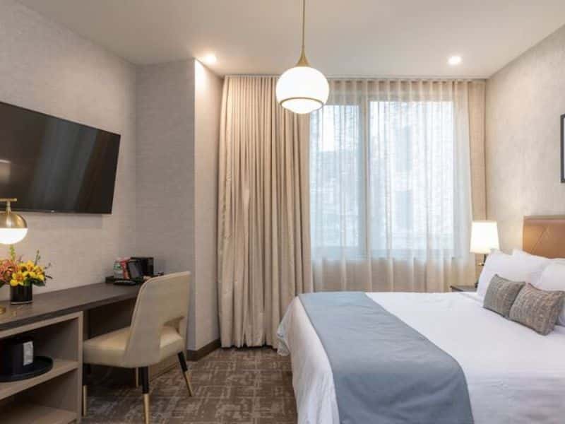 Stylish hotel room at Broadway Plaza Hotel featuring a flat-screen TV, desk, and comfortable bed with contemporary decor, located in the Nomad district of New York City.