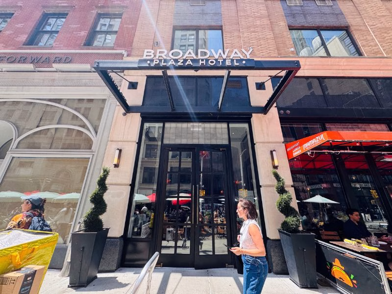 Broadway Plaza Hotel entrance with modern signage, stylish design, and outdoor dining area in vibrant Nomad district of New York City.