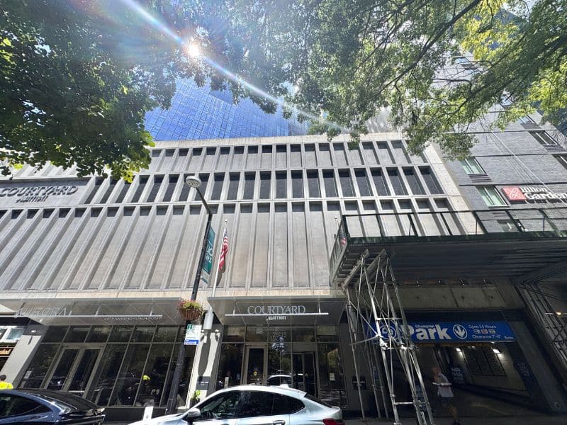 Courtyard by Marriott exterior view in Long Island City, showcasing modern architecture, nearby trees, and a parking facility.
