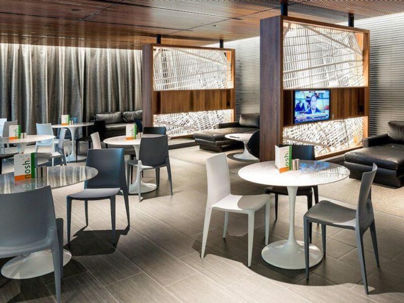 Modern lounge area in Courtyard Long Island City featuring stylish tables and chairs, ambient lighting, and a cozy seating arrangement with a television.