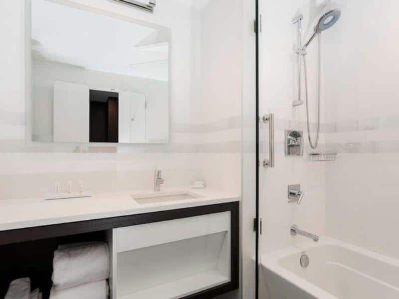 Modern hotel bathroom featuring a sleek design with a bathtub, shower, and vanity, reflecting the amenities at Courtyard Long Island City.