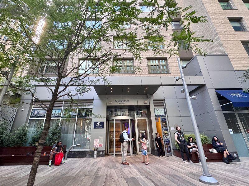 DoubleTree by Hilton New York Times Square South entrance, featuring guests and staff, surrounded by greenery and modern architecture, in the vibrant Garment District.