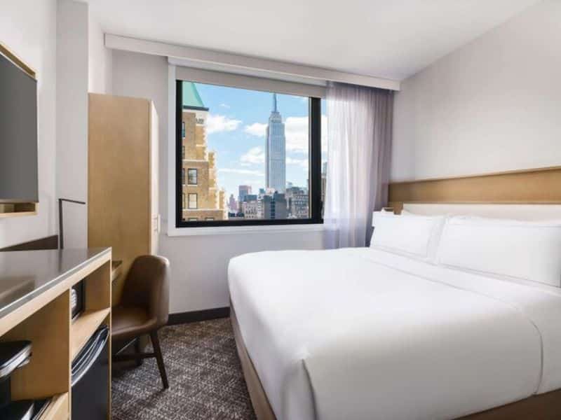 Cozy hotel room at DoubleTree by Hilton New York Times Square South with view of the Empire State Building, featuring a king bed, modern decor, and a work desk.