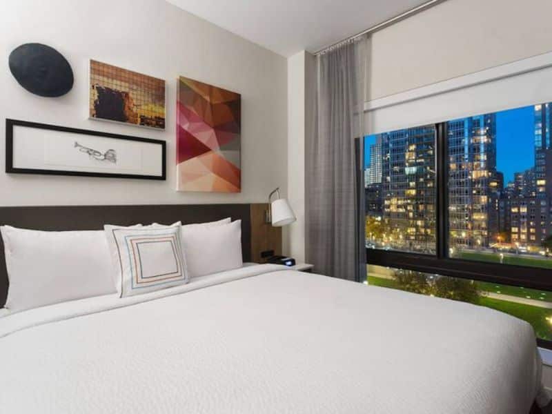 Cozy hotel room at Fairfield Inn & Suites by Marriott New York Manhattan/Central Park, featuring a king-size bed, modern decor, and city views through large windows, ideal for travelers seeking comfort and convenience near Central Park.