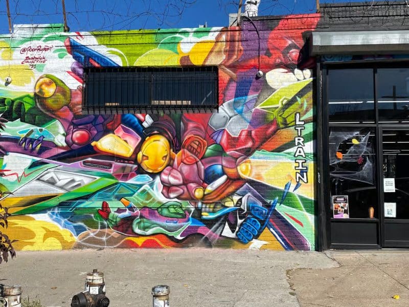 Colorful street art mural featuring vibrant characters and designs, showcasing Brooklyn's artistic culture, with the word "TRAIN" prominently displayed.