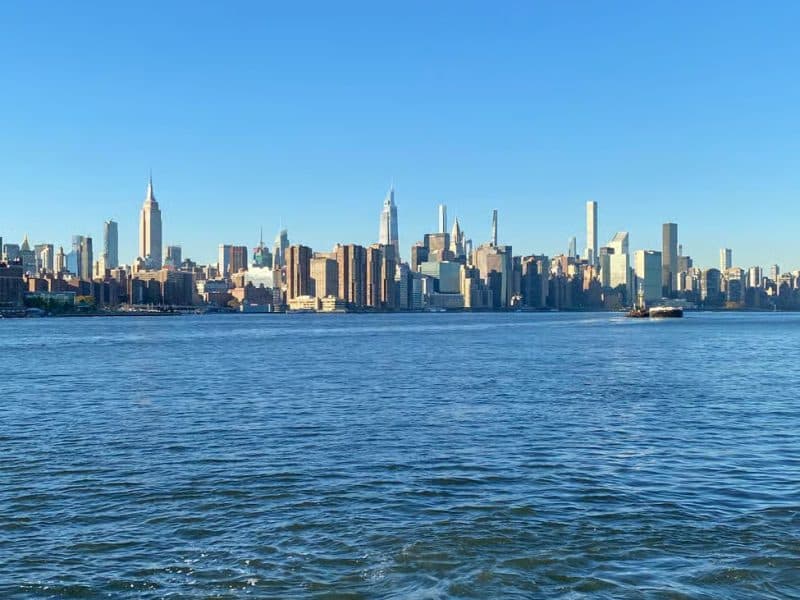 Brooklyn waterfront view showcasing the Manhattan skyline, featuring iconic skyscrapers under a clear blue sky, relevant to the French-guided walking tour exploring Bushwick and Williamsburg's vibrant culture.